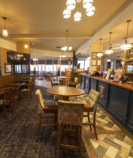 Interior dining area of a pub with a bar and a TV.