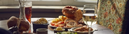 A pork roast dinner on a table, surrounded by sides, drinks and another roast dinner.