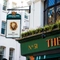 A close up view of the exterior pub sign on the exterior wall of The Golden Lion. The sign features the Greene King logo and an illustration of a lion's head above the words "The Golden Lion, Soho".