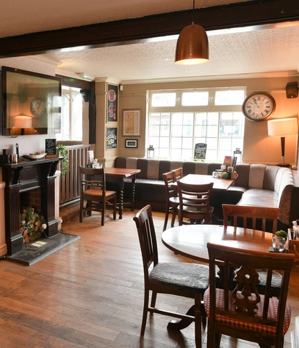 Interior dining area of a pub with a TV and a fireplace.