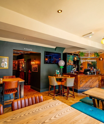 The bar and interior restaurant seating area at The Windmill Inn in York, with upholstered bench seats, TVs on the wall, and a fireplace.