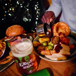 A image of gravy being poured over a roast meal within the interior restaurant and seating area of Greene King Pub venue.
