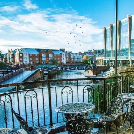 Exterior of the venue with seats overlooking the river with a bridge