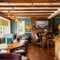 An interior restaurant seating area at The Walkford, with an upholstered booth seat in front of the leaded windows, wooden beams on the ceiling, and a brick fireplace.