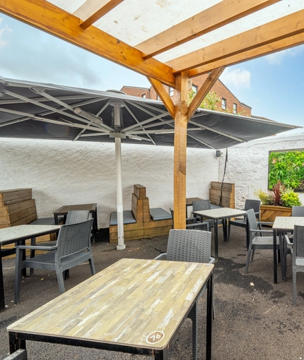 The exterior beer garden seating area at the Counting House, with a large shade umbrella, an under cover section, and padded booth seats.