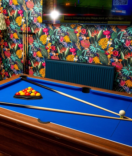 The interior games area at The Windmill Inn in York, with a pool table, a TV on the wall, and a brick fireplace.