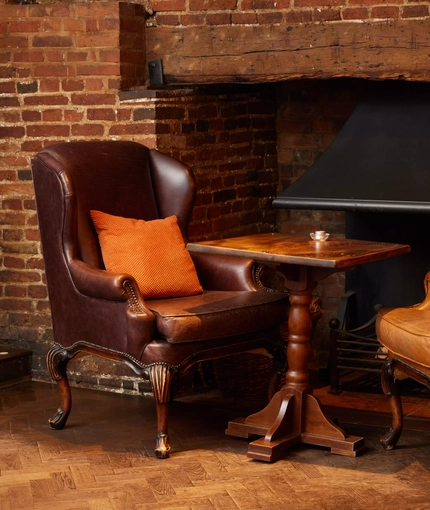 2 armchairs either side of a table infront of a fireplace 