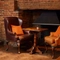 2 armchairs either side of a table infront of a fireplace 