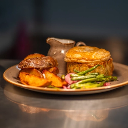 An image showing a plated pie, wedges and vegetable dish sat on an interior food counter cabinet at a Chef & Brewer venue. 