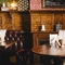 The wood panelled interior restaurant seating area at the Masons Arms, with upholstered booth corner seats, a fireplace, and grape vines carved into the coving around the ceiling.