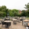 The exterior beer garden seating area at The Richmond Arms in Bournemouth, with tables and chairs on a paved patio area; wooden picnic tables on the grass; string lights overhead; and an outdoor TV.