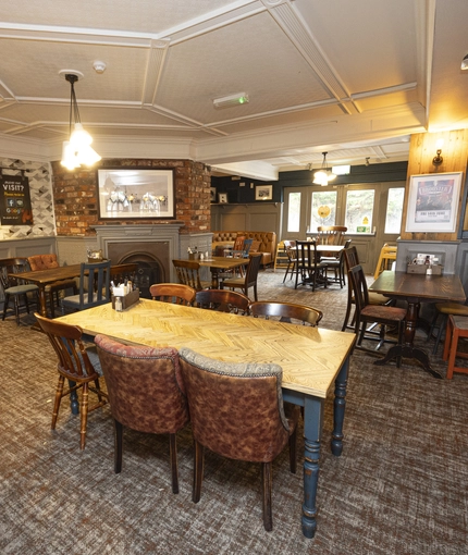 Interior dining area of a pub with a fireplace.