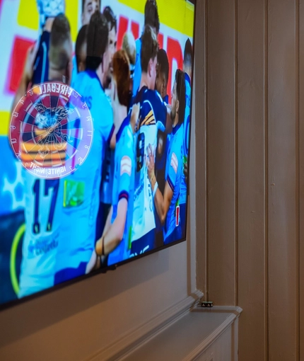 A close up view of the illuminated dartboard at the Devonshire Arms, and the large TV on the wall adjacent to it.
