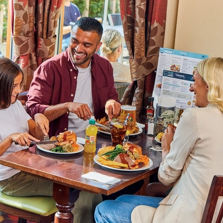 family sitting round a table in a restaurant eating a roast dinner