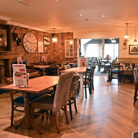 Interior dining area of a pub with a TV, a fireplace and a claw machine.