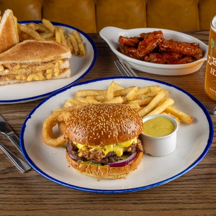 Various plated dishes for Burger of the Month July on a table.