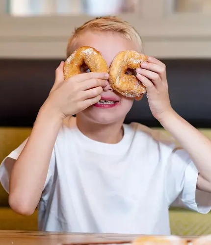 Boy holding two donuts over his eyes