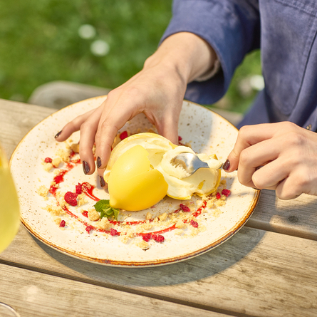 An image of a customer sat at a table within the exterior beer garden enjoying a Lemon Cheesecake Bomb dessert and cocktail style drink at a Chef & Brewer venue.
