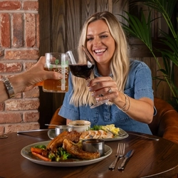Two friends seated at the restaurant area in a Greene King Community Pubs with Food venue enjoying mains off the specials menu.