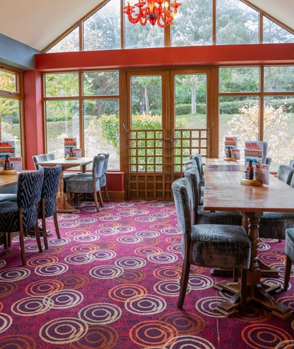 The interior restaurant seating area in the conservatory of The Royal Horse in Warwick, with wooden tables and upholstered seats.