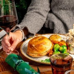 A plated Mushroom Galette on a festive decorated wooden table, the torso of someone seated at the table is visible.