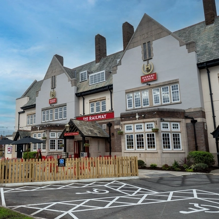 The exterior facade, signage, beer garden seating area, and accessible car parking spaces, at The Railway in Meols.