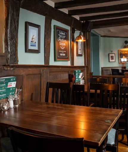 An interior restaurant seating area at The Ship, with wood panelling on the walls, and wooden beams on the walls and ceiling.