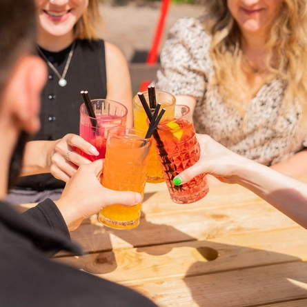 A lifestyle image of a mixed group of people enjoying cocktails in a beer garden.