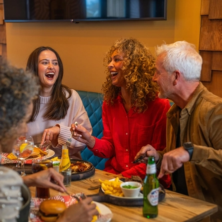 A mixed group of people seated at an indoor table enjoying a meal.