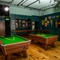 The interior games area at the Lord Raglan, with two pool tables, bar stool seating, and a TV on the wall.