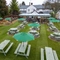 An aerial view of the exterior beer garden seating area at the Tredegar Arms, including the picnic tables and shade umbrellas on the lawn, the paved seating area, and the undercover area.