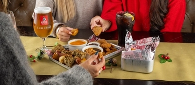 An interior shot of people celebrating Christmas and enjoying festive food in the restaurant/seating area at a Flaming Grill venue.