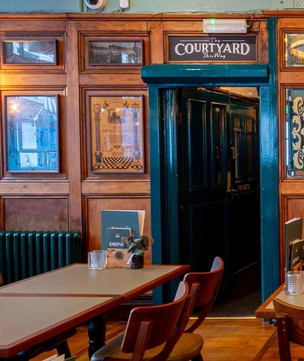 The wood panelled bar and interior restaurant seating area of Adam & Eve, with a view of the entrances to the courtyard and the snug.