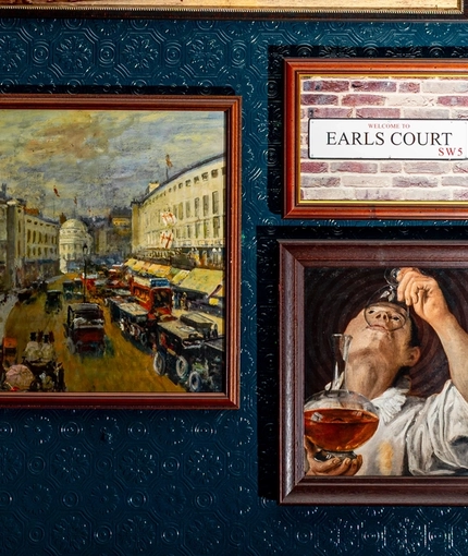 A close up view of framed artwork on a wall inside The Earls Court Tavern.