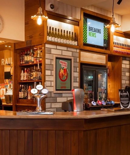The bar inside The Railway in Meols, with TVs on the wall above the bar.