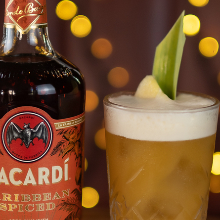 a bottle of rum and a cocktail sitting on a wooden table of a pub