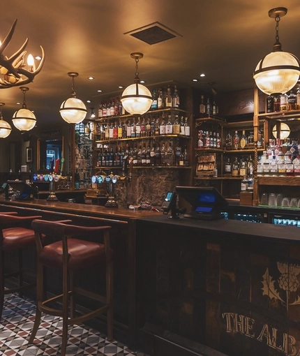 The dark wood panelled bar and the interior restaurant seating area at the Albanach in Edinburgh.
