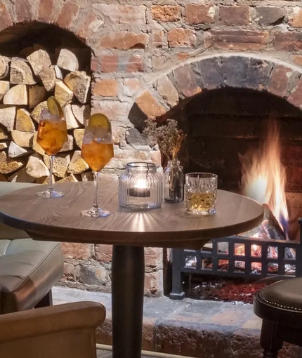 small circle table positioned in front of open fireplace with 2 large cushioned armchairs