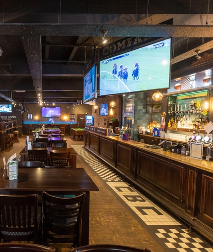 The restaurant and bar areas of The Cold Beer Company, with some televisions above the bar.