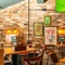 An interior restaurant seating area at The Windmill Inn, with framed artwork, wall lights, and a TV on the exposed brick wall.