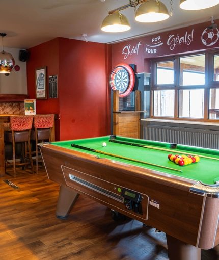 The interior restaurant seating and gaming area, with a dartboard and a pool table.