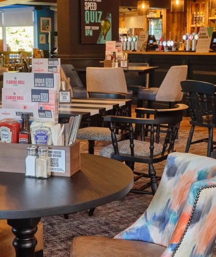 The bar and interior restaurant seating area at The Carousel, with wooden tables, upholstered seats, and TVs on the walls.