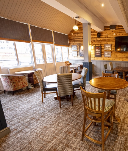 Interior dining area of a pub with a bar and a TV.