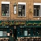 The exterior facade, signage, and seating area of the Royal George in Euston; with a large golden lantern hanging above the door, and flower boxes above the windows.
