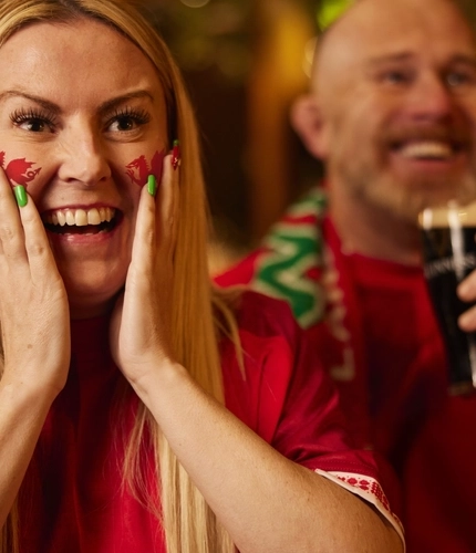 An image of a woman wearing a sport team shirt, watching a sporting event.