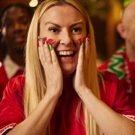 An image of a woman wearing a sport team shirt, watching a sporting event.