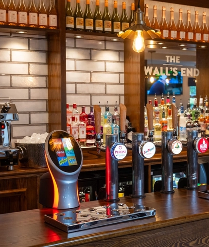 A close up view of the bar inside The Wall's End in Wallsend, with bottles of wine and alcoholic spirits on wooden shelves behind the counter.