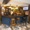 Interior pub area of a pub with stools, a TV and a dartboard.