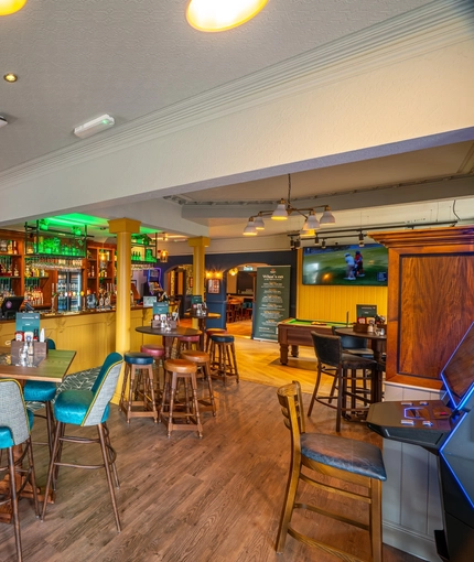 The bar and interior restaurant seating area of the Malvern Tavern, with a pool table, and a TV on the wall.