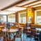 The interior restaurant seating area at The Walkford in Walkford, with a fireplace, upholstered booth seats in front of the leaded windows, and wooden beams on the ceiling.